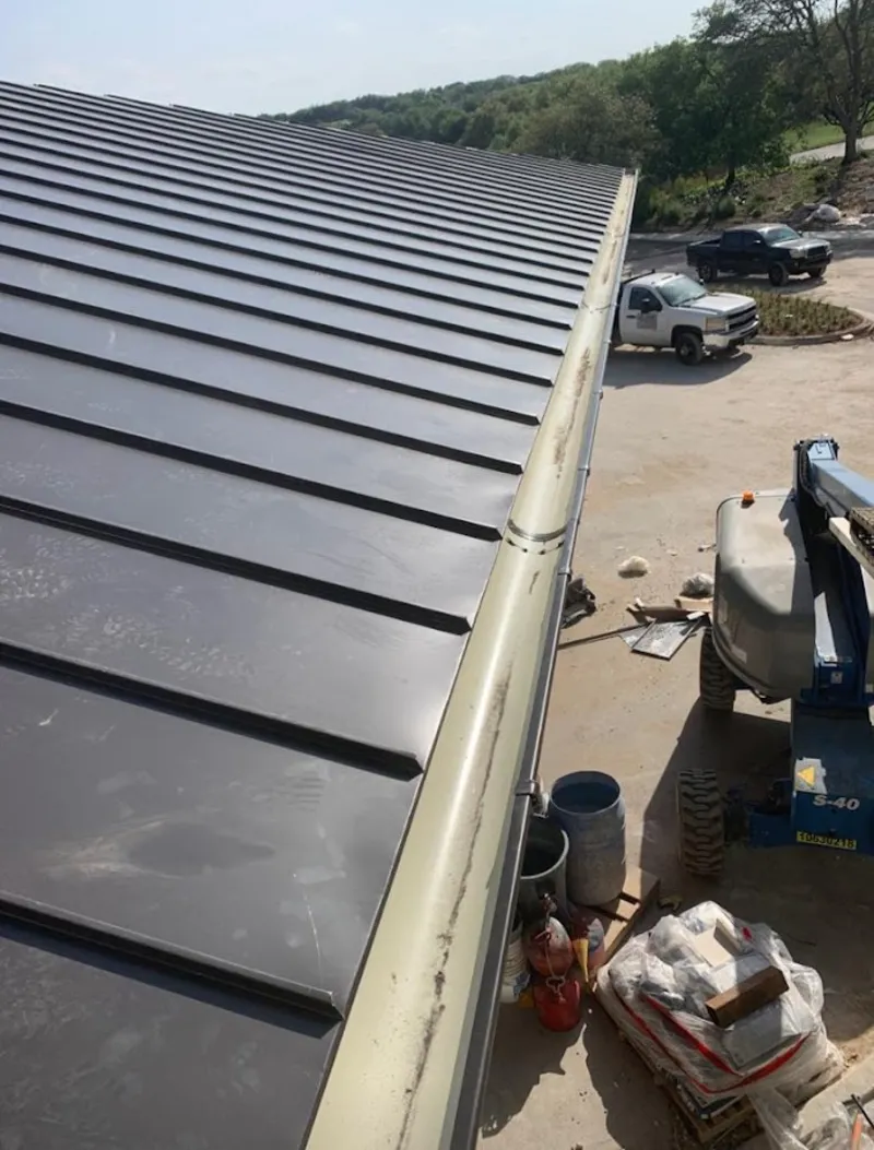 Standing seam panel and gutter detail on a metal roofing jobsite in Luling